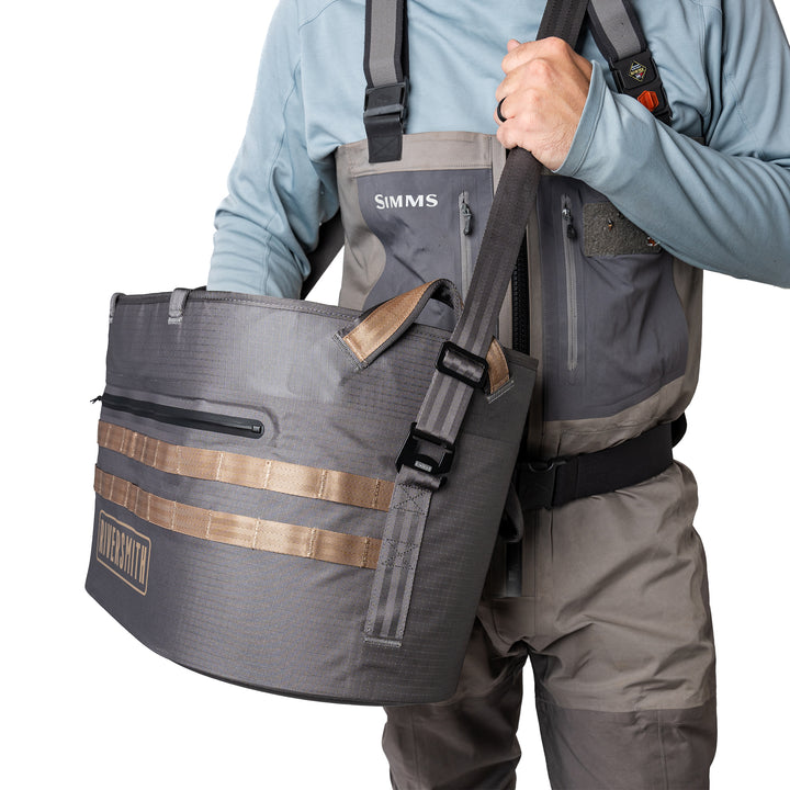 Person wearing a gray wader with a matching bag, holding the bag with one hand.